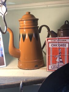 A caramel coloured tall coffee pot with a row of brown triangles around the middle, points downward