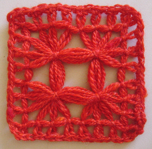 A completed tied lace motif made with red wool.