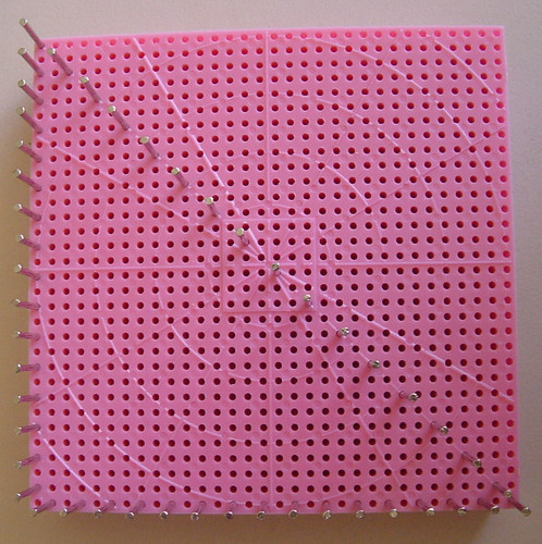 Small pin loom with pins added to weave a traingle.