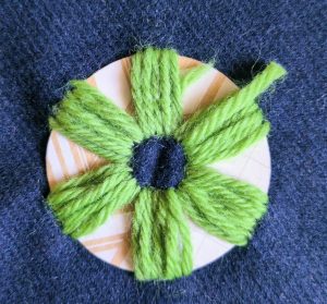 A layer of green wool has been stitched over the six thick stripes and through the fabric.