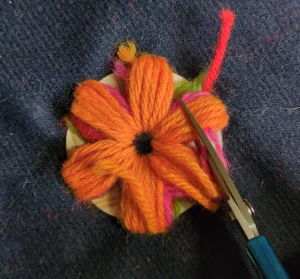 A pair of scissors cuts through each stripe of stitches, leaving equal lengths of yarn on the edges of the inner and outer edges.