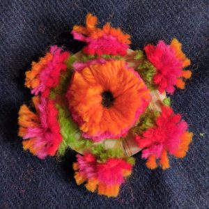 All of the threads have been cut, creating a rough pompom surrounded by six smaller pompoms.