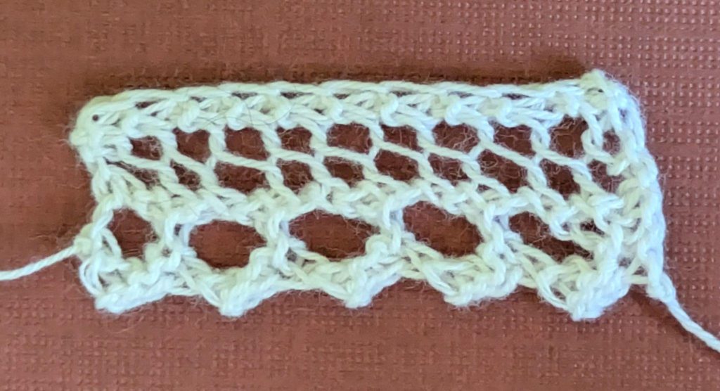 A narrow knitted lace edging with a design of large, single yarn overs.