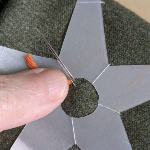 Bringing the needle up through the fabric, next to where it went down in the previous step.