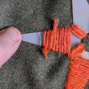 Stitching over the yarn tails to hold them in place.