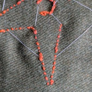 The back of the work. An outline of very small stitches next to each other.