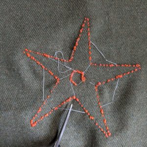 Cutting the basting stitches on the back of the work.