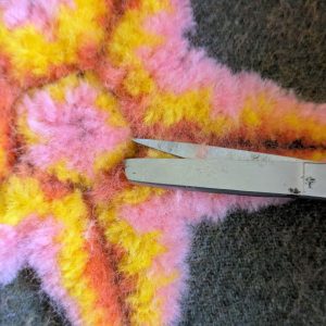 Trimming off the halo of fuzz with the scissors held horizontally.